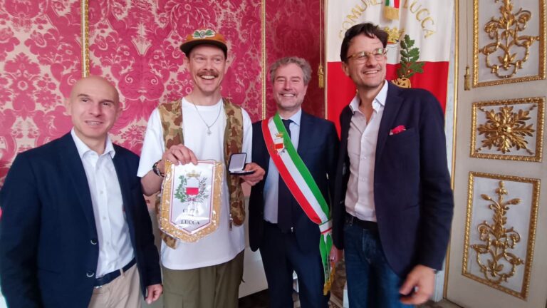 LUCCA COMICS & GAMES DÀ IL BENVENUTO AL GIRO D’ITALIA. KARL KOPINSKI RICEVE LA MEDAGLIA DELLA CITTÀ, INCONTRA FRANCESCO MOSER DAVANTI ALL’INSTALLAZIONE A LUI ISPIRATA E CON LUI ED ELISA SCARLATTA VISITA LA MOSTRA DEDICATA AGLI EROI DEL CICLISMO “KARL KOPINSKI: WEARING THE PINK”